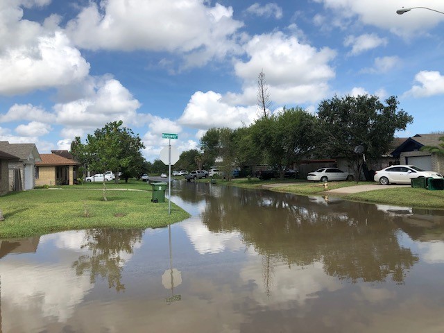 Photo at the same intersection, nearly 18 hours later (2 PM October 2) showing continued high water of 1 to 2 feet in the streets. 