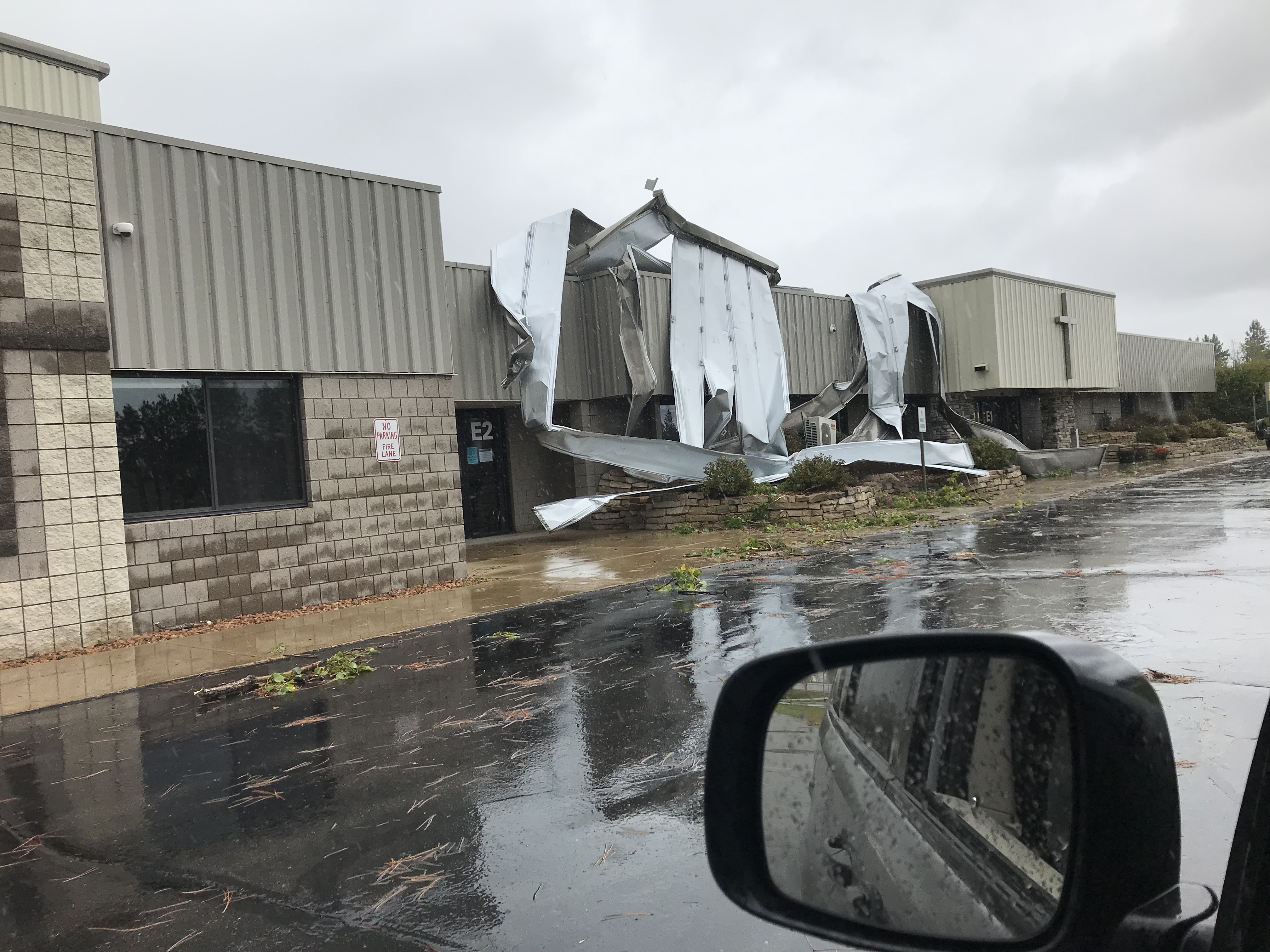 Damage to roof of a business, with sheet metal hanging down