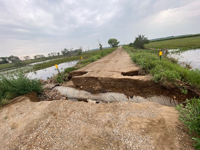 A local road north of De Smet, South Dakota was washed away exposing a culvert. Just beyond the culvert the road is washed away on both sides of the road. Water is on both sides of the road in the fields.
