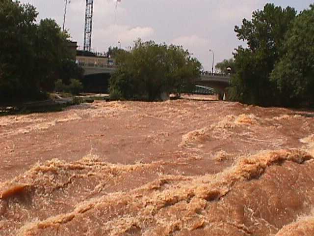 The Reedy River surges through the west end of downtown Greenville, South Carolina, on 29 July 2004