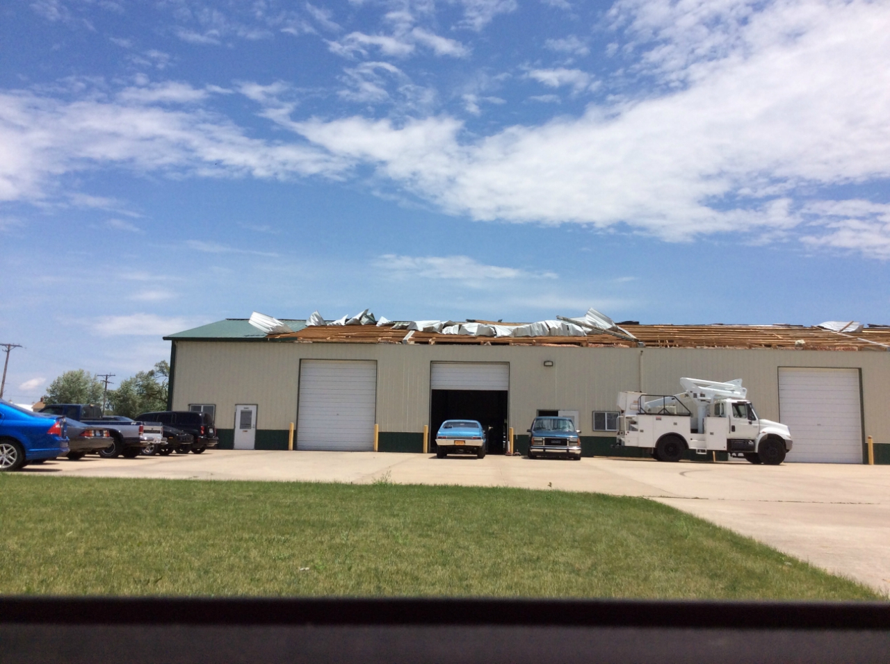 Photo showing damage from straight-line winds near Morris. Part of the roof has been removed from a metal industrial building.