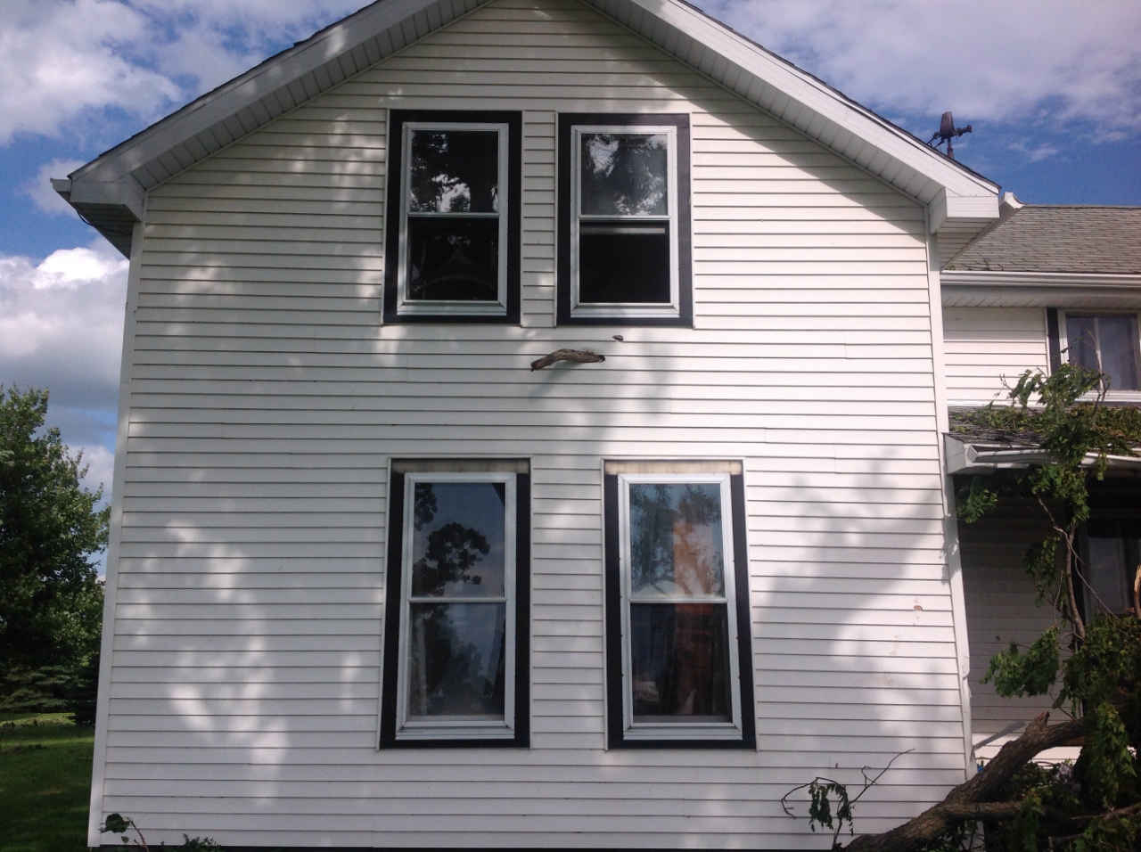 Photo showing damage from a tornado near Grant Park. A tree branch has been impaled into the side of a house.