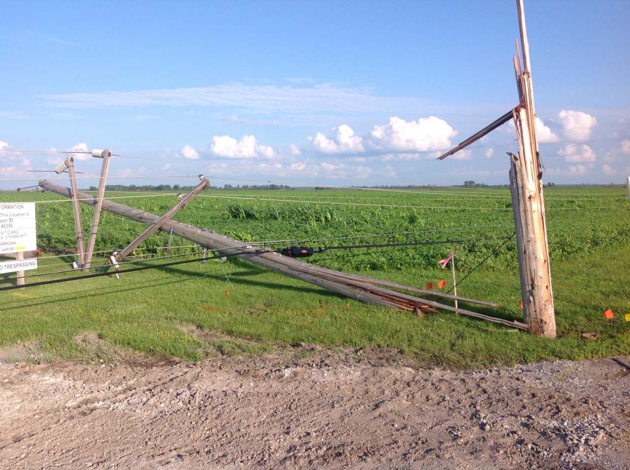 Photo showing damage from a tornado near Lowell. A power pole has been snapped and the power lines are lying on the ground.