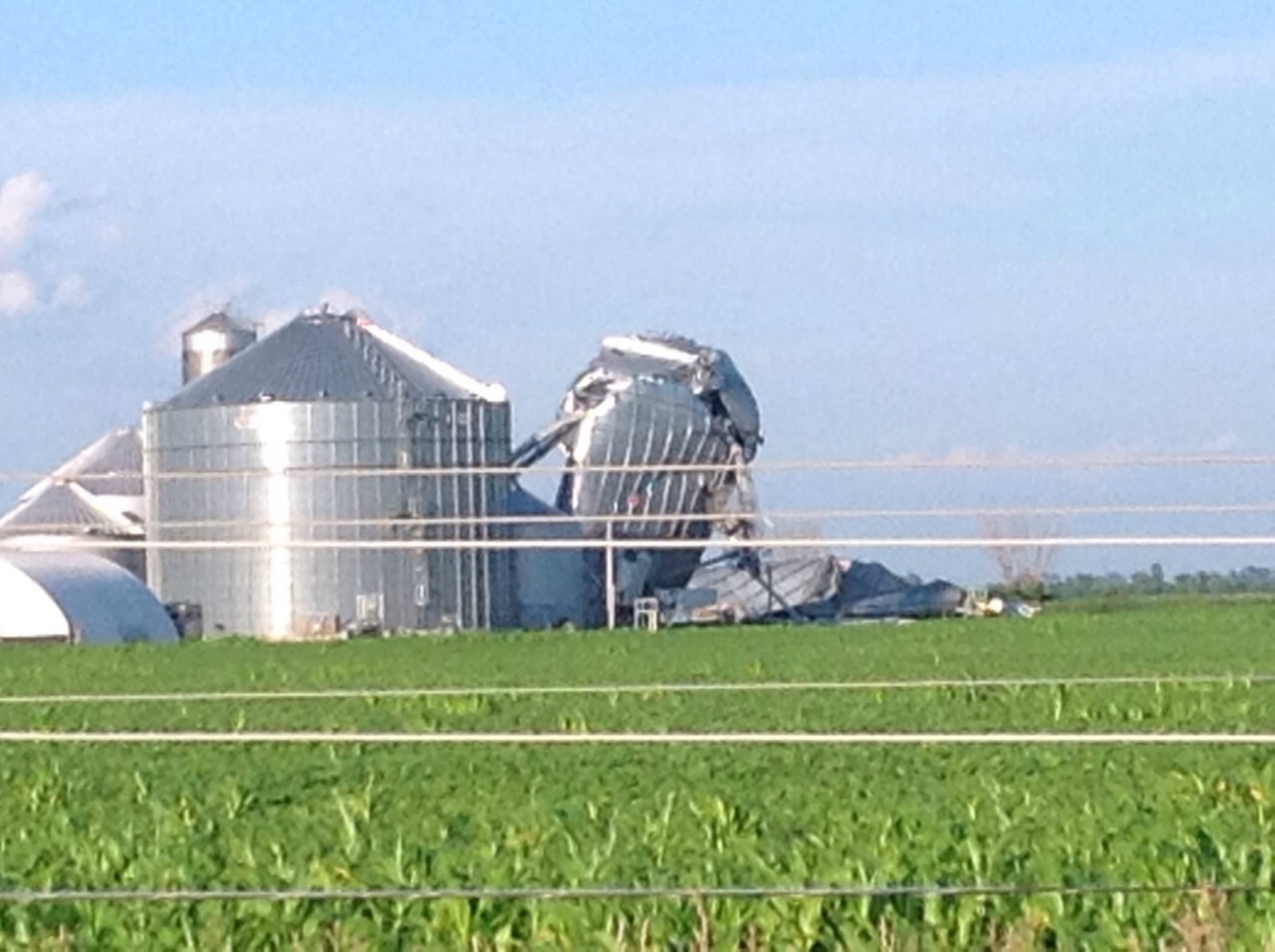 Photo showing damage from a tornado near Lowell. Metal grain silos have been damaged, with one partially collapsed.