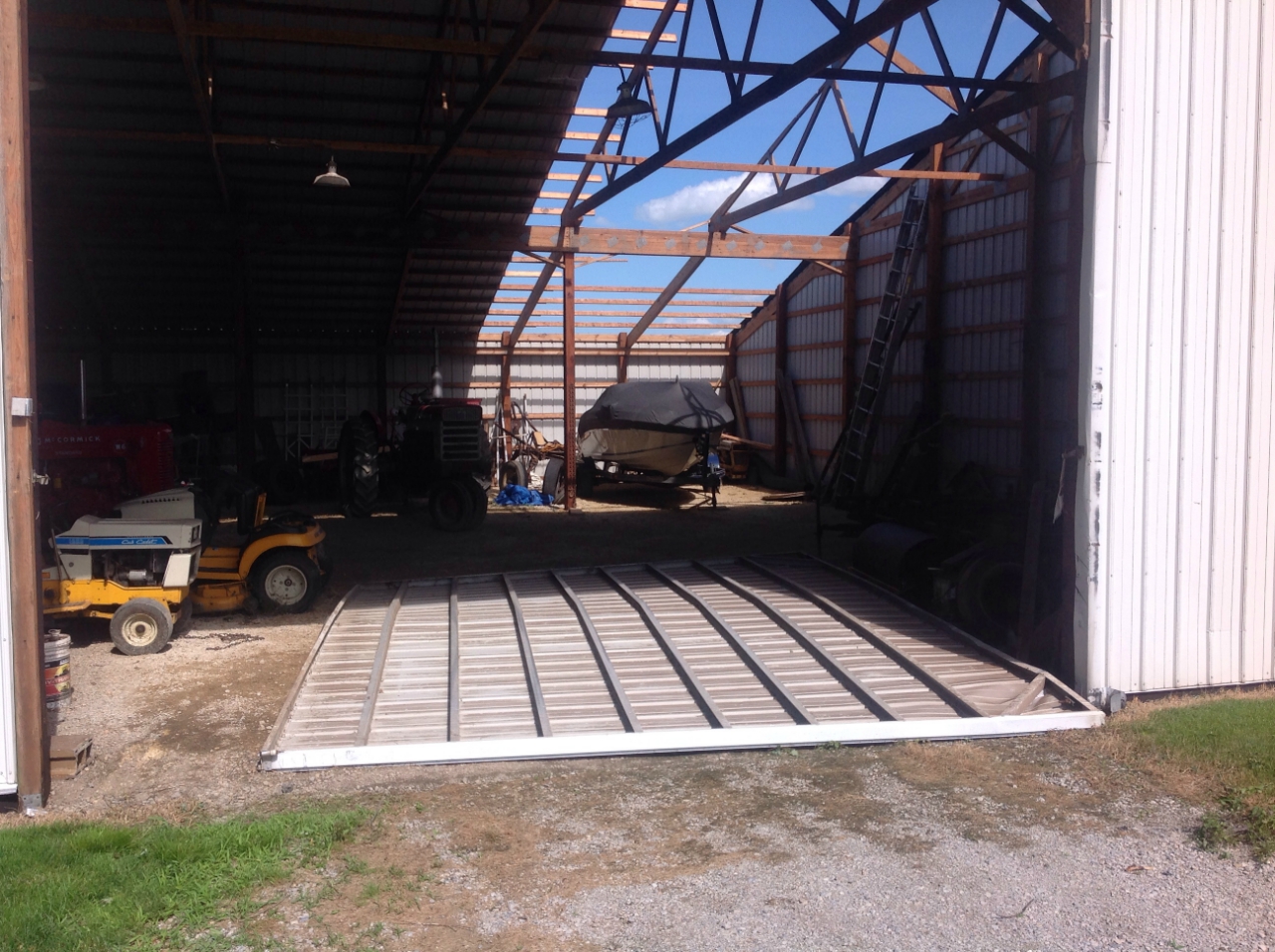 Photo showing damage from a tornado near Grant Park. A portion of the roof has been removed from a metal farm outbuilding.