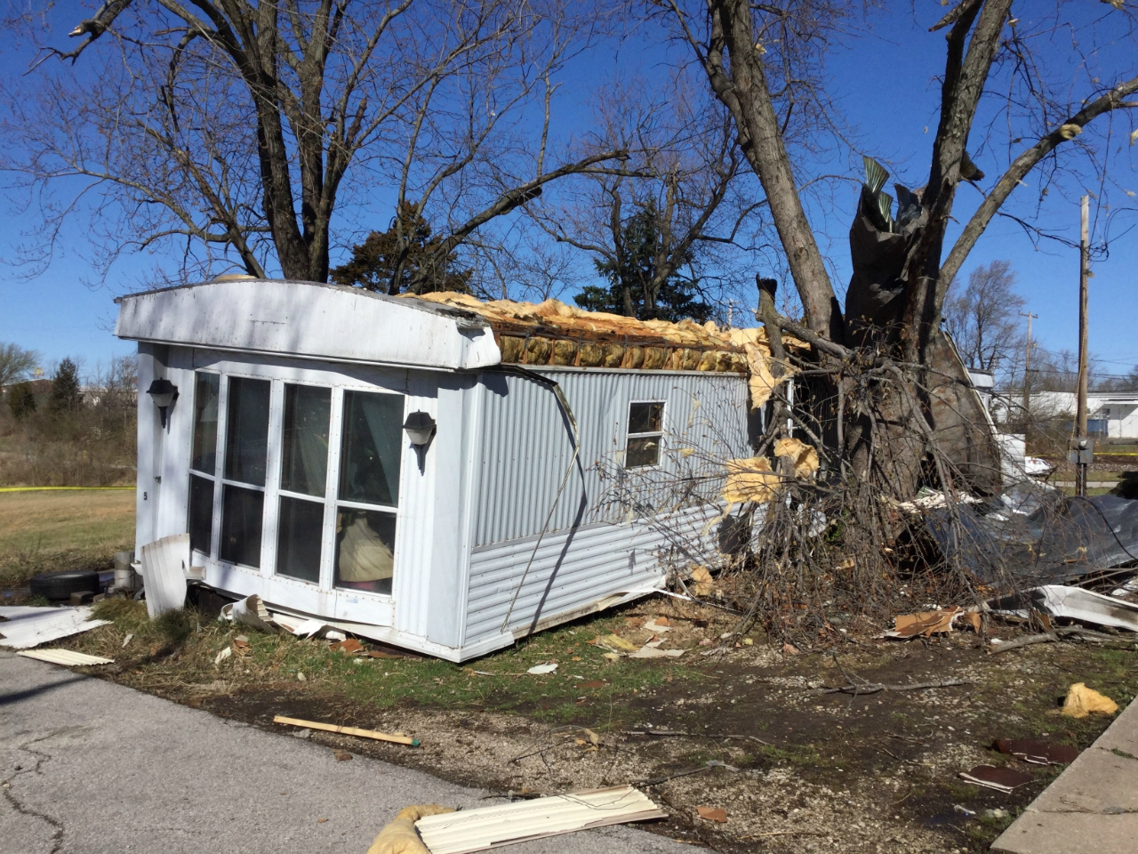 Photo of mobile home with roof removed and pushed off of foundation blocks on Edith Street.