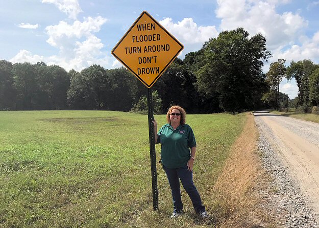 White County Emergency Manager Tamara Jenkins stands next to a Turn Around Don't Drown<sup>TM</sup> sign near Big Creek along Albion Road just east of Albion (White County) in early October, 2018.
