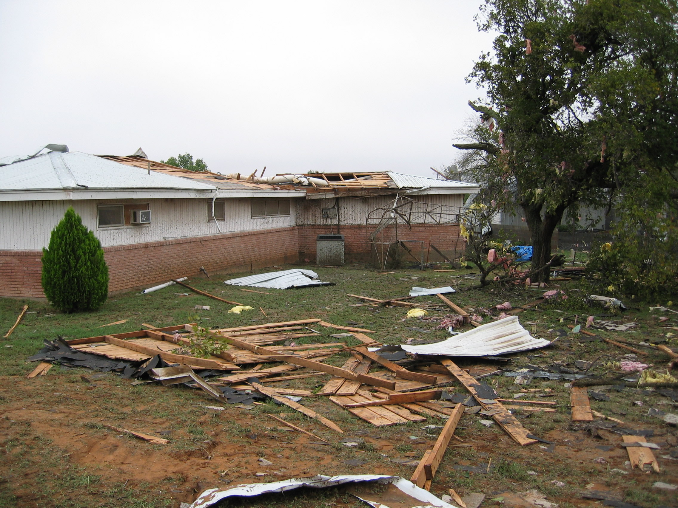 Second photo of house sustaining F1 tornado damage showing roof blown from the house.