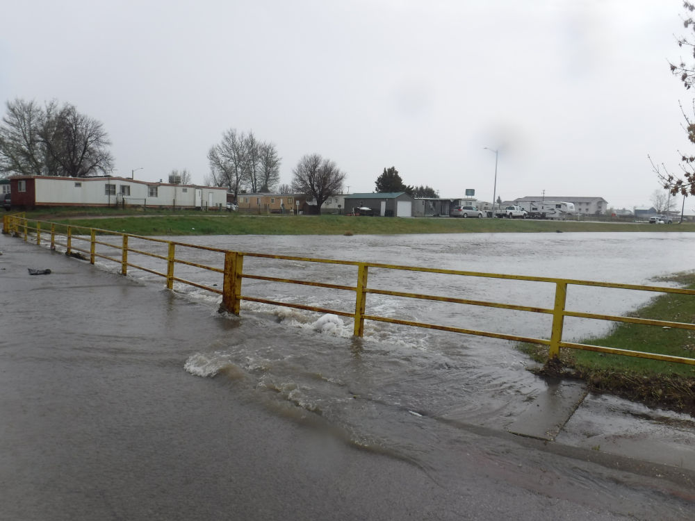 Flooding across a road, through yellow railings